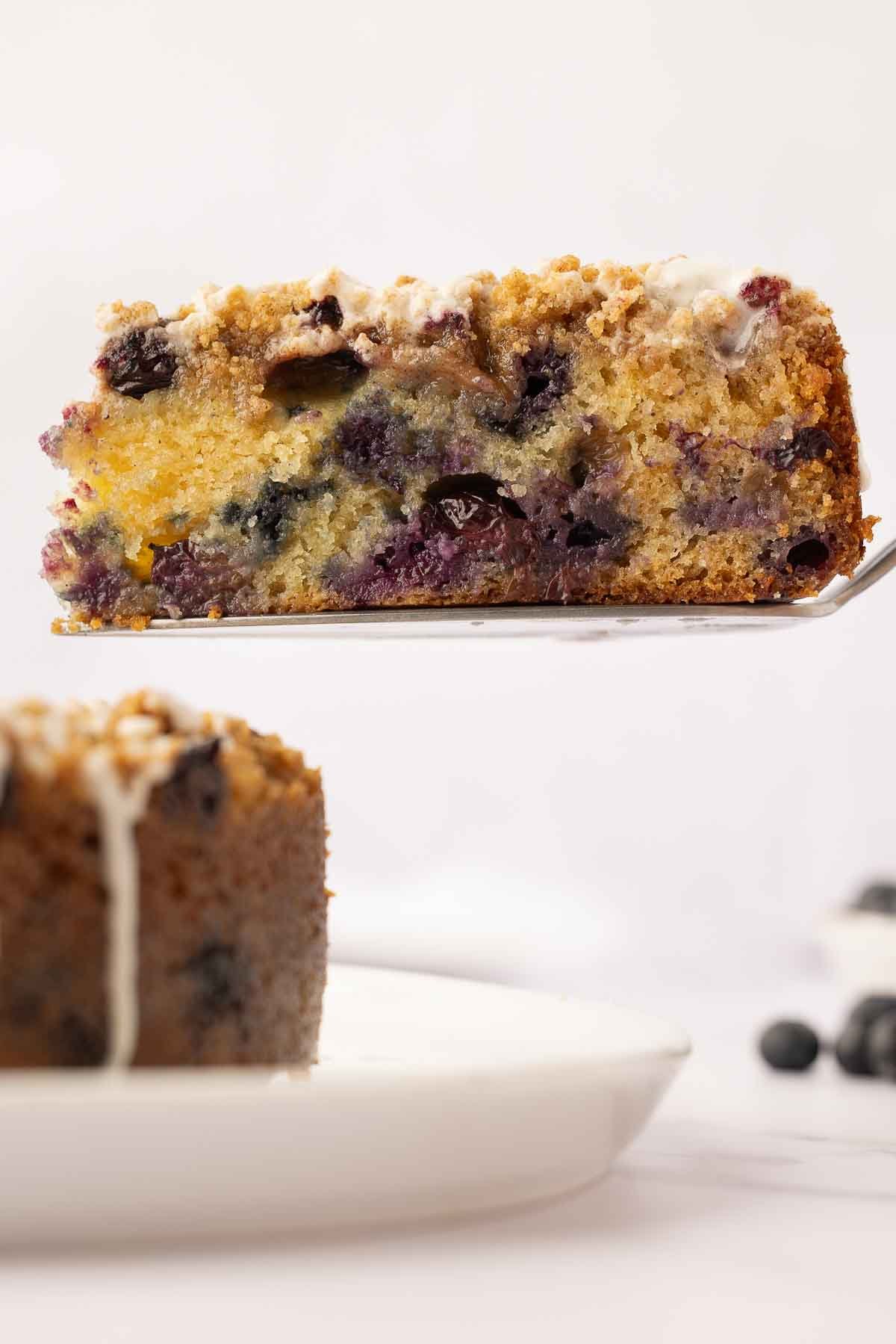 Sour Cream Blueberry Coffee Cake slice lifted up on cake spatula.